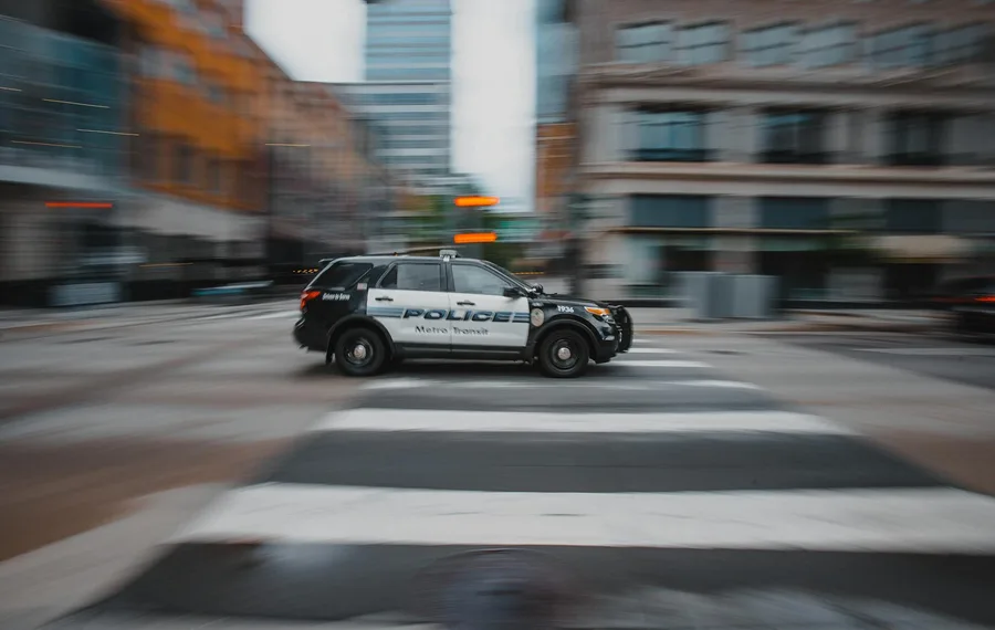 Blurry image of a police car moving quickly in an urban street showcasing motion and speed.