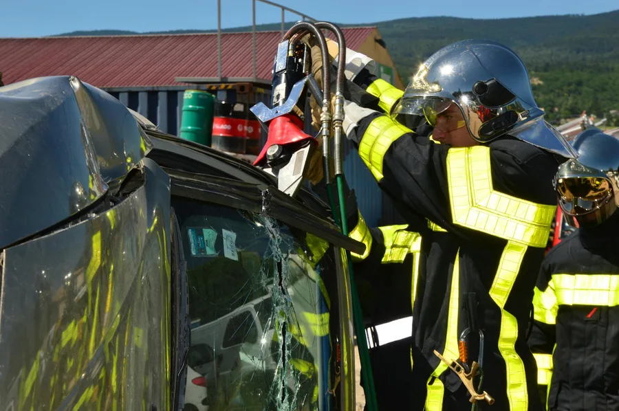 Firefighters in action using rescue tools at a car accident scene outdoors.