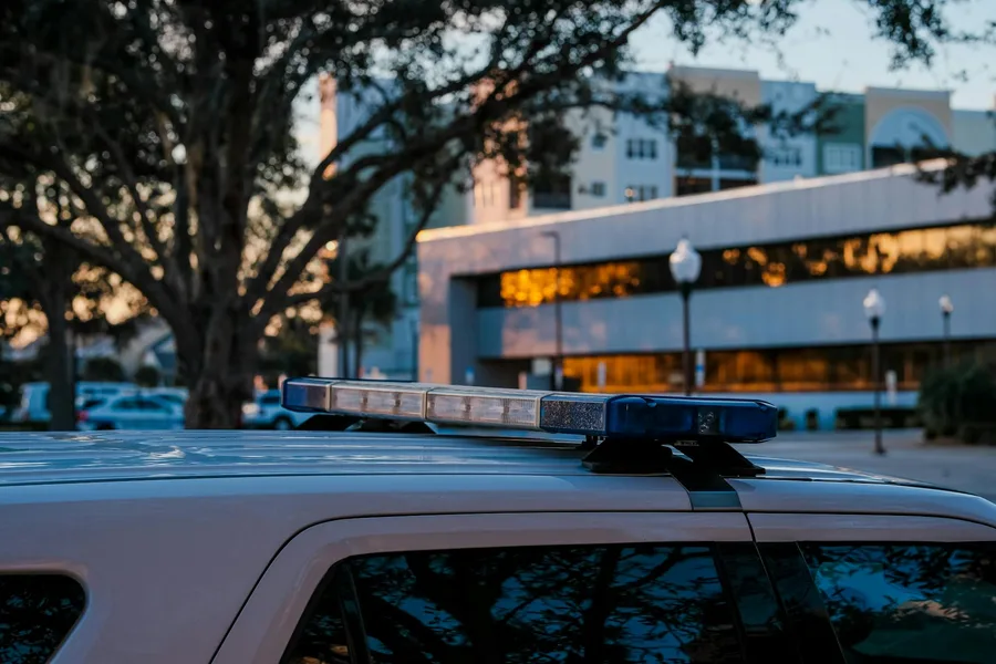 Close-up of police vehicle with emergency lights in front of urban buildings at dusk.