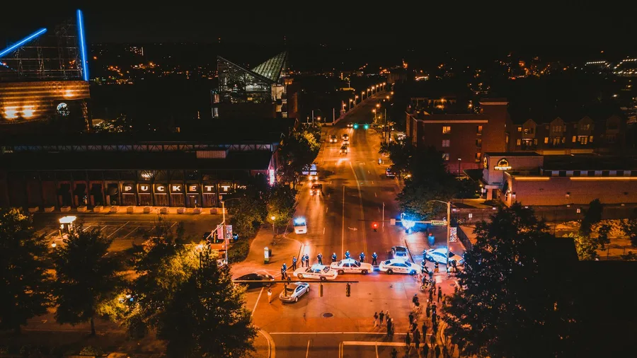A vibrant aerial view of Chattanooga at night featuring illuminated streets and police cars.
