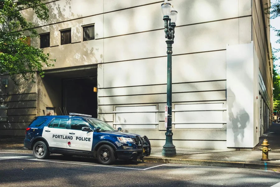 A Portland police SUV parked on a city street near a building.