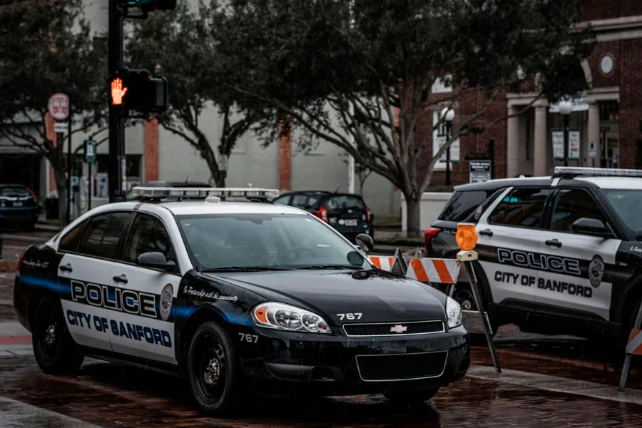 City of Sanford police cars parked on wet urban streets with traffic signals and buildings.