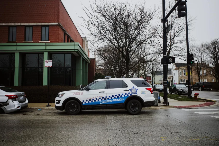 A Chicago police SUV parked on a city street near an intersection on a cloudy day.