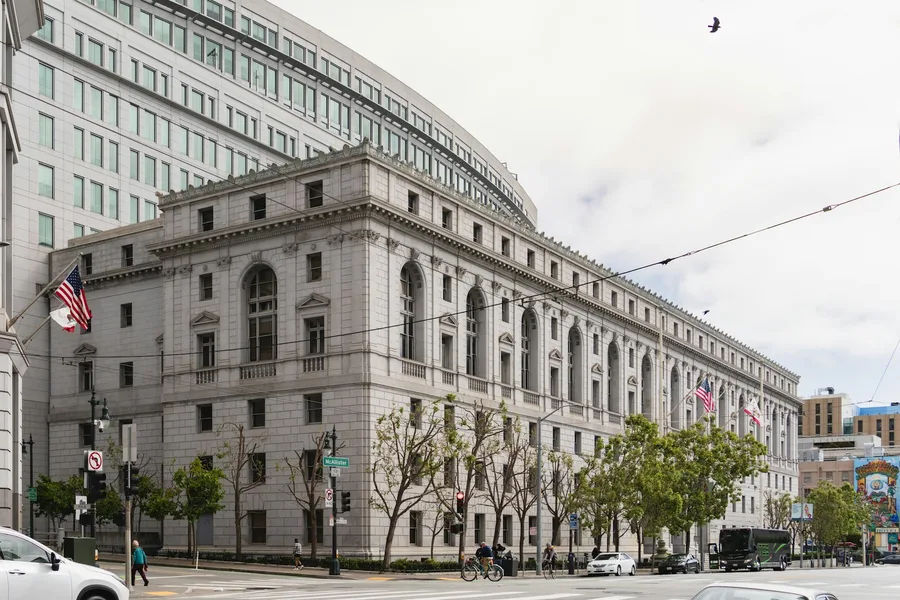 Elegant neoclassical courthouse in San Francisco with American flags outside.
