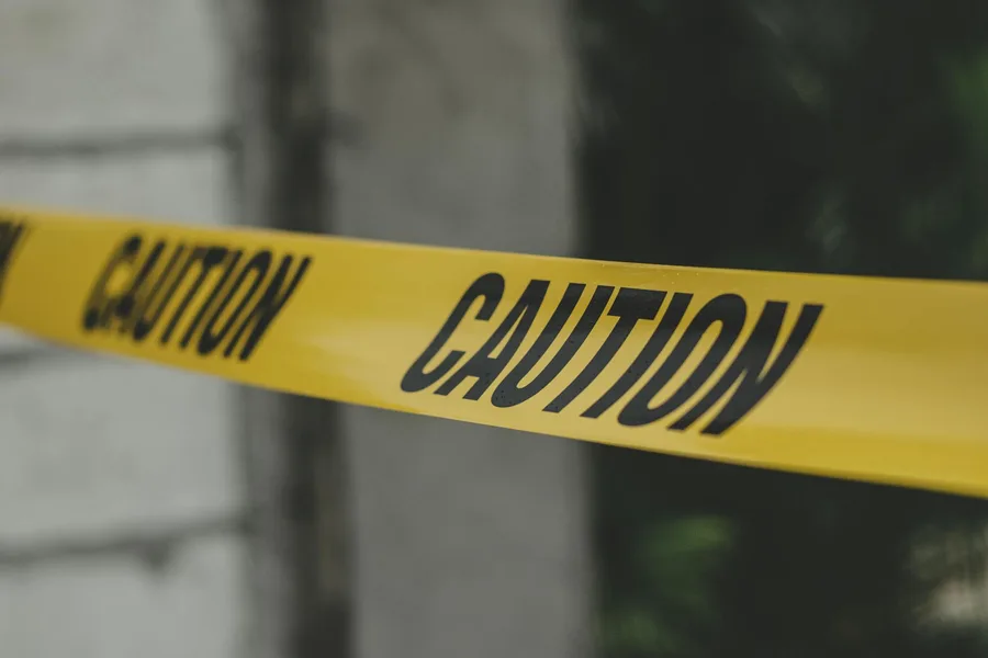 Close-up view of yellow caution tape creating a warning barrier outdoors.