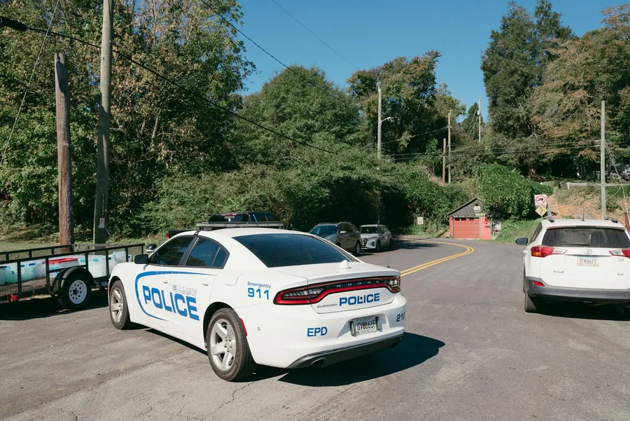 A police car parked at a suburban road intersection on a sunny day.