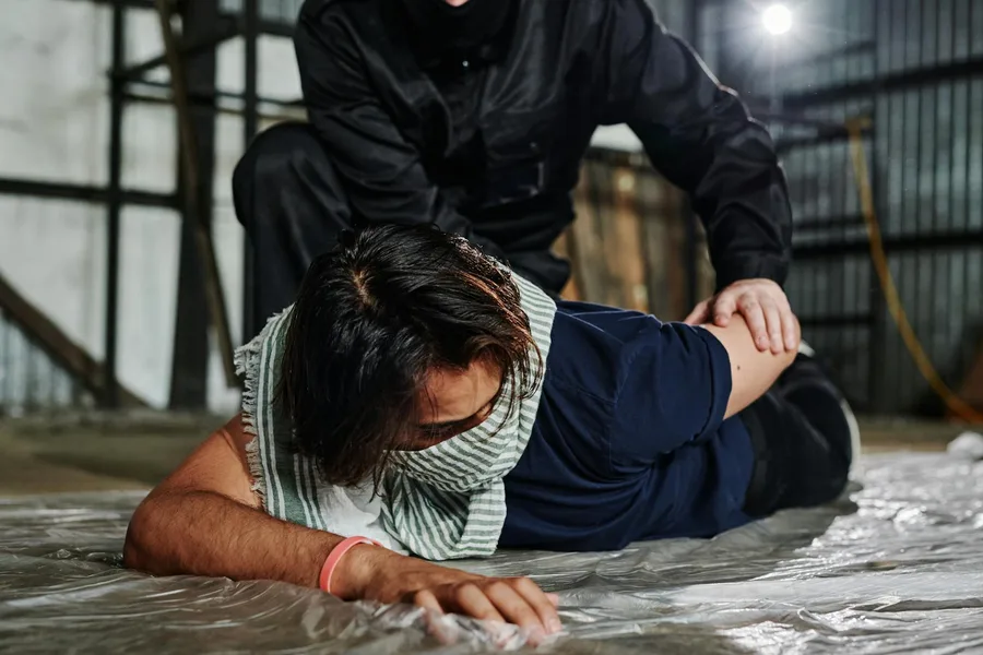 Masked officer arrests man in warehouse, showcasing urban conflict.