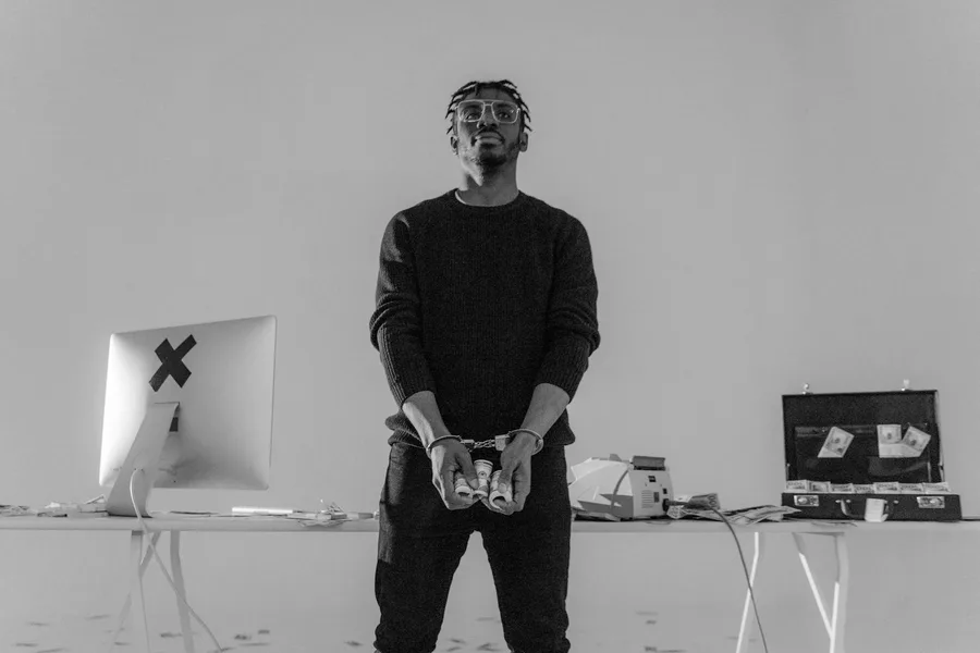 Grayscale image of a handcuffed man holding cash, symbolizing crime and consequences.