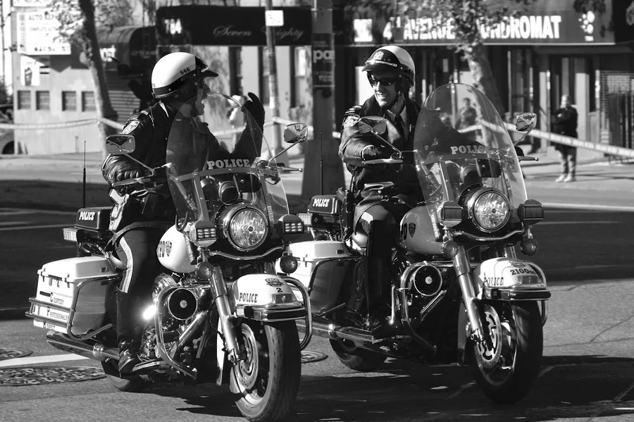 Two police officers on motorcycles patrol city streets of New York, NY.