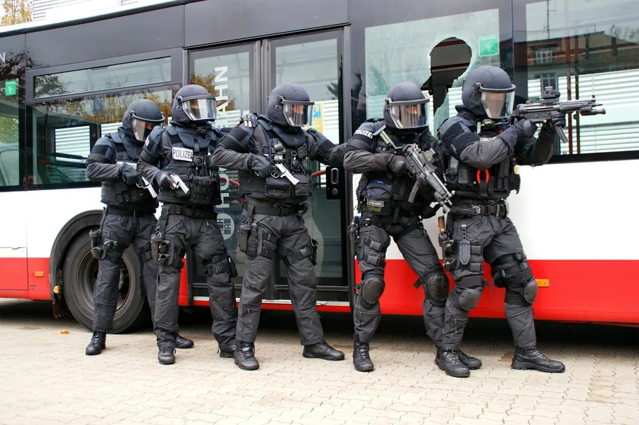 Armed police officers in tactical gear performing an operation on a bus.