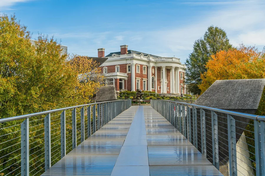 Elegant mansion with white columns seen from a modern pedestrian bridge in Chattanooga, Tennessee.