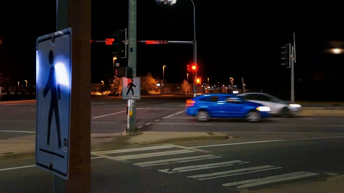 Blurred cars speeding through a city intersection at night under stop lights.