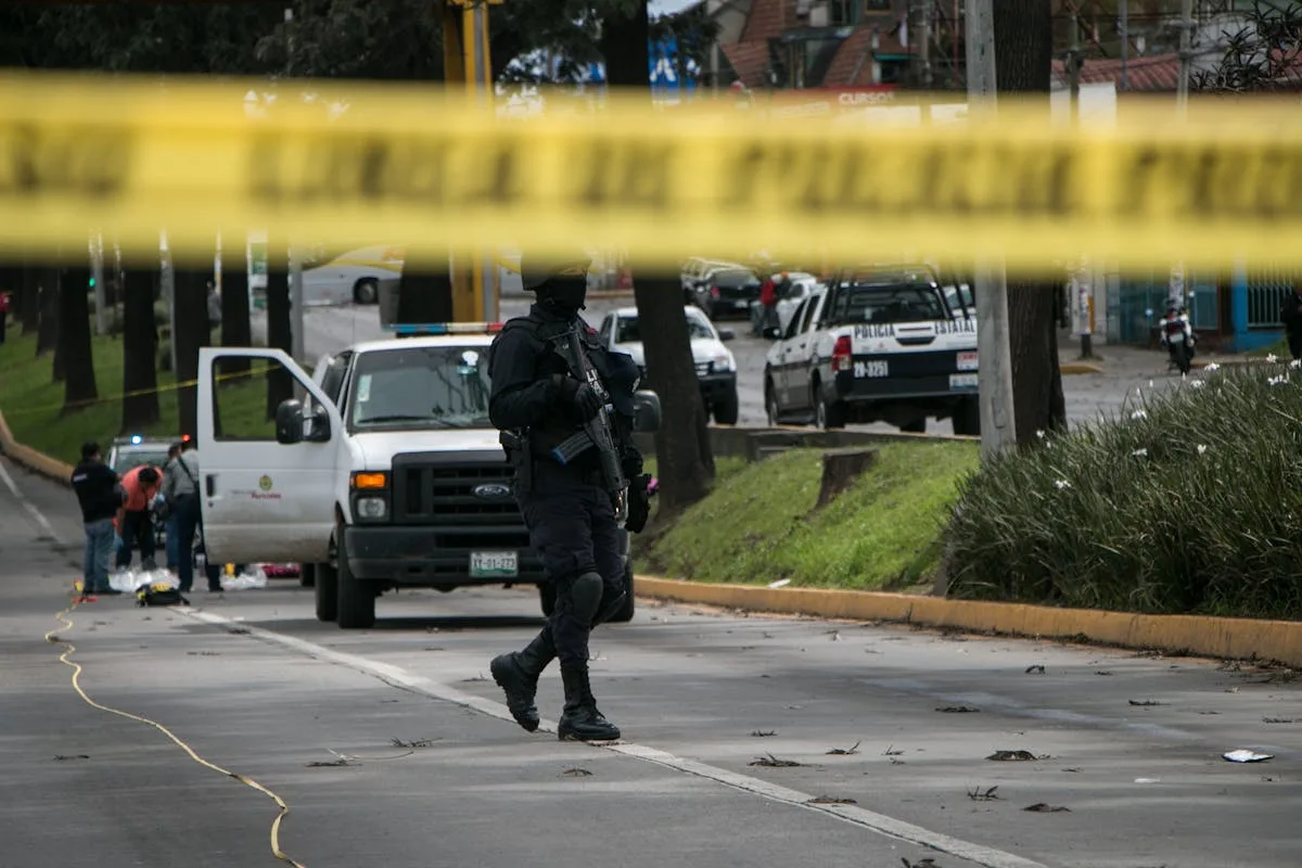 Police officers investigate and secure a crime scene in an urban street with caution tape.
