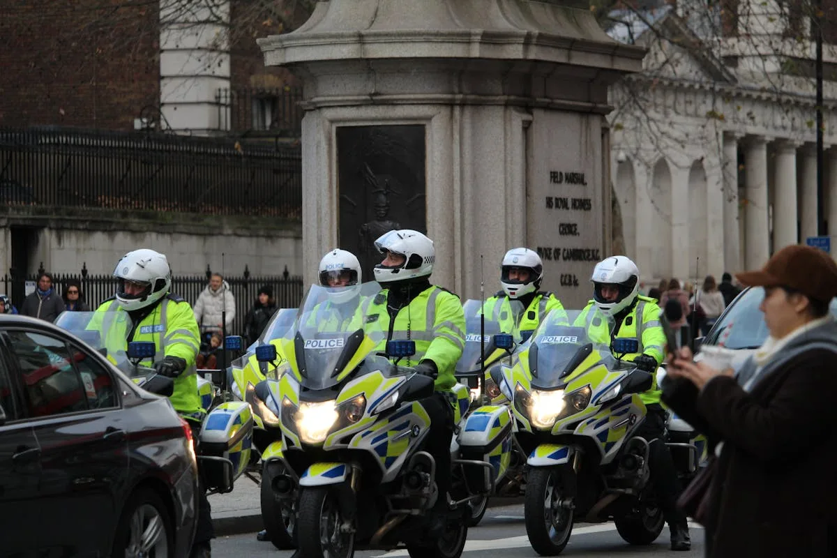 Police officers on motorcycles patrolling an urban intersection with onlookers.

