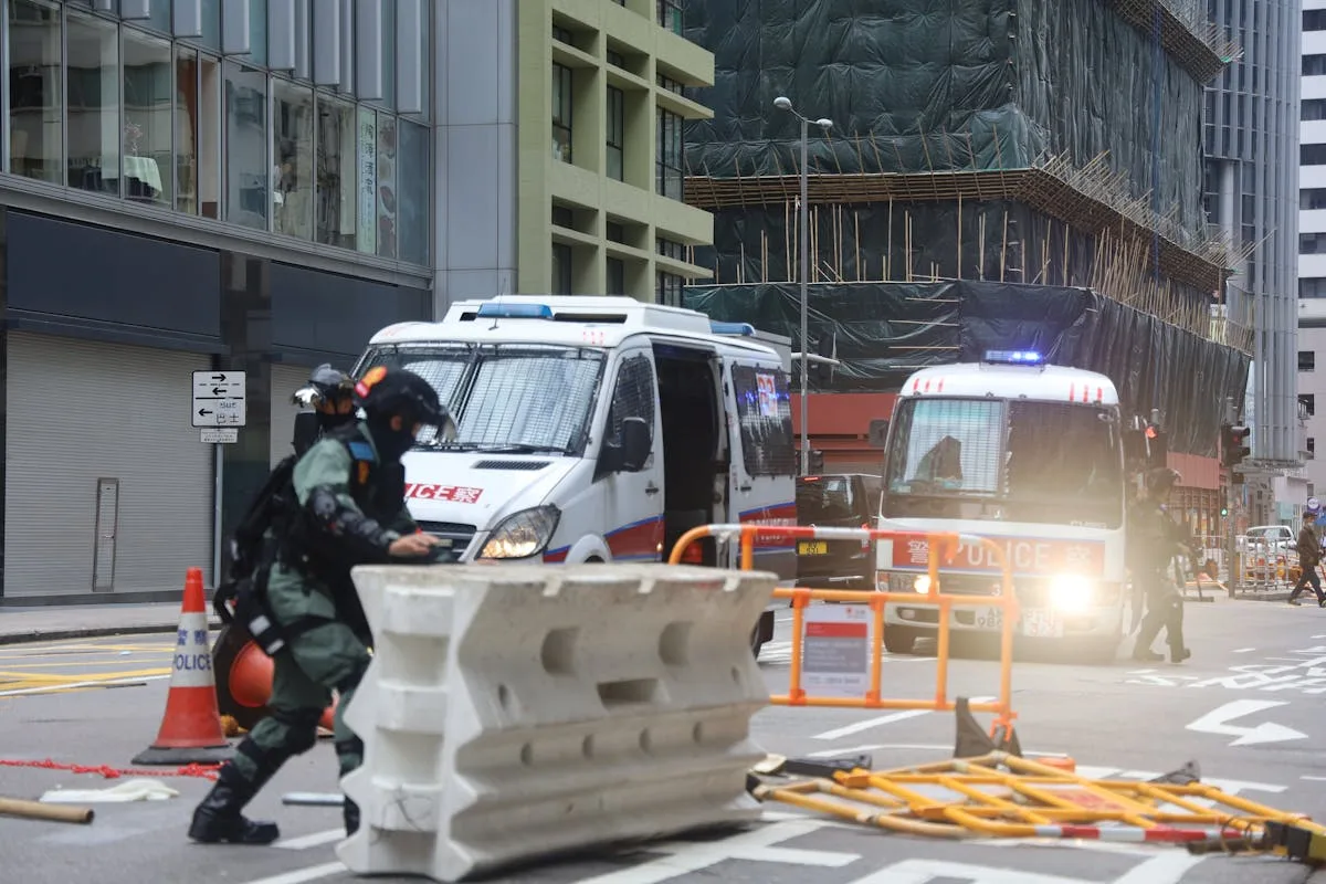 Police presence with barricades and vans on a city street indicating a security operation.
