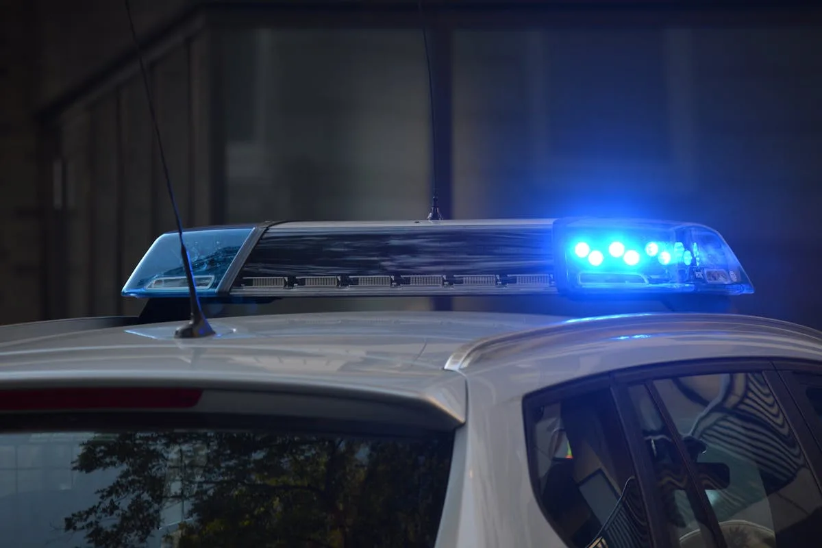 Close-up of a police car's flashing blue lights in an urban environment.
