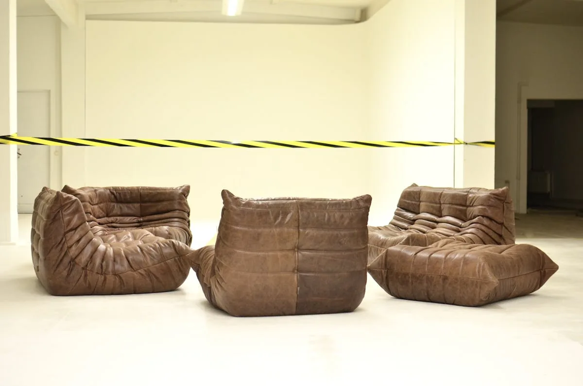 Leather couches placed in empty room under bright striped barrier tape during renovation process