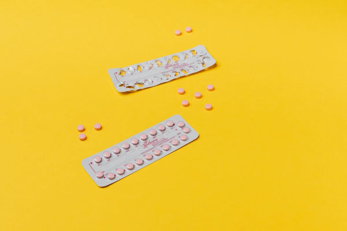 Pink pills and blister packs on a vibrant yellow background, symbolizing healthcare.