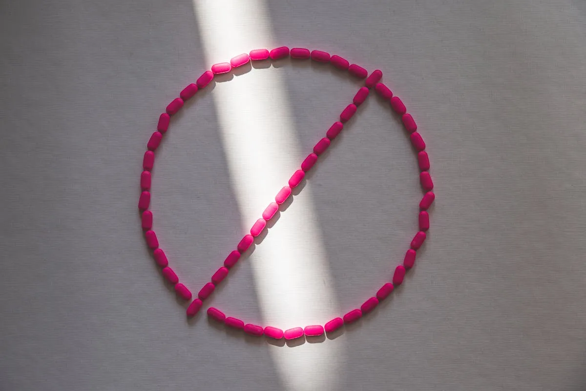 Pink pills arranged in a prohibition symbol in sunlight, symbolizing drug restrictions.
