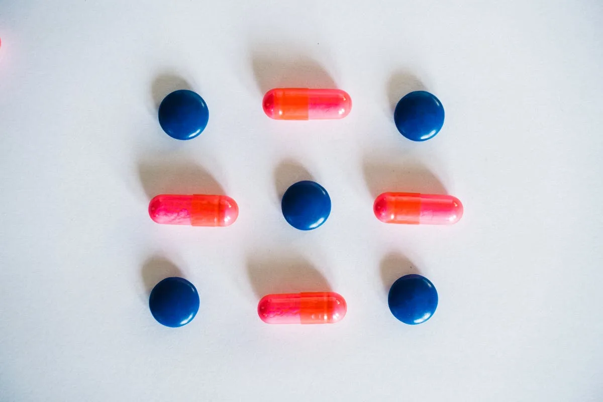 Various blue and pink pills and capsules arranged on a white background, showcasing medication.