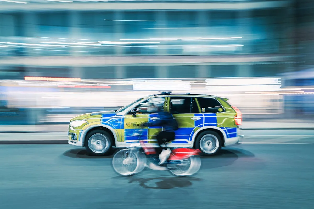 Dynamic motion blur shot of a cyclist and police car on a city street at night.
