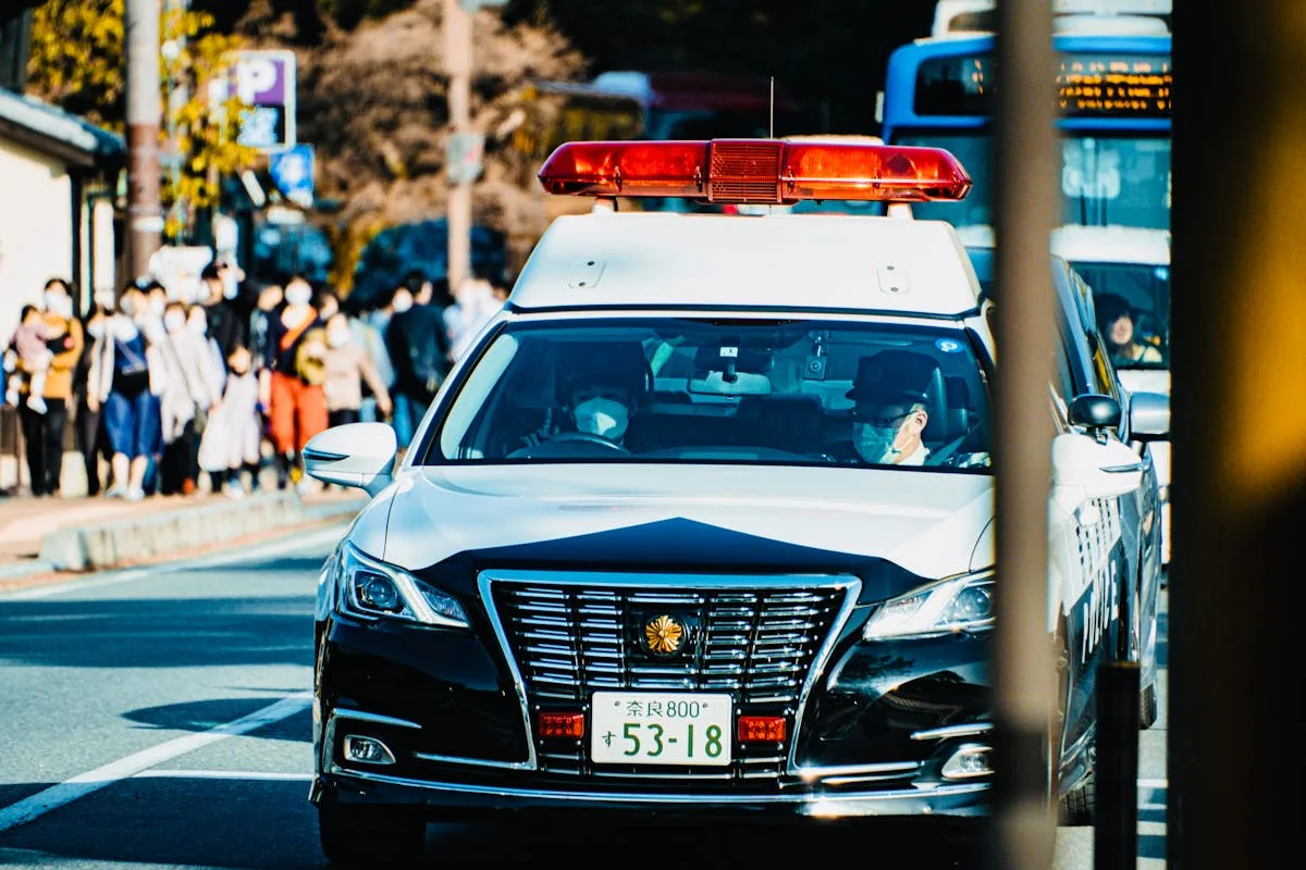 Police car navigating through city traffic, showcasing urban life and community security.
