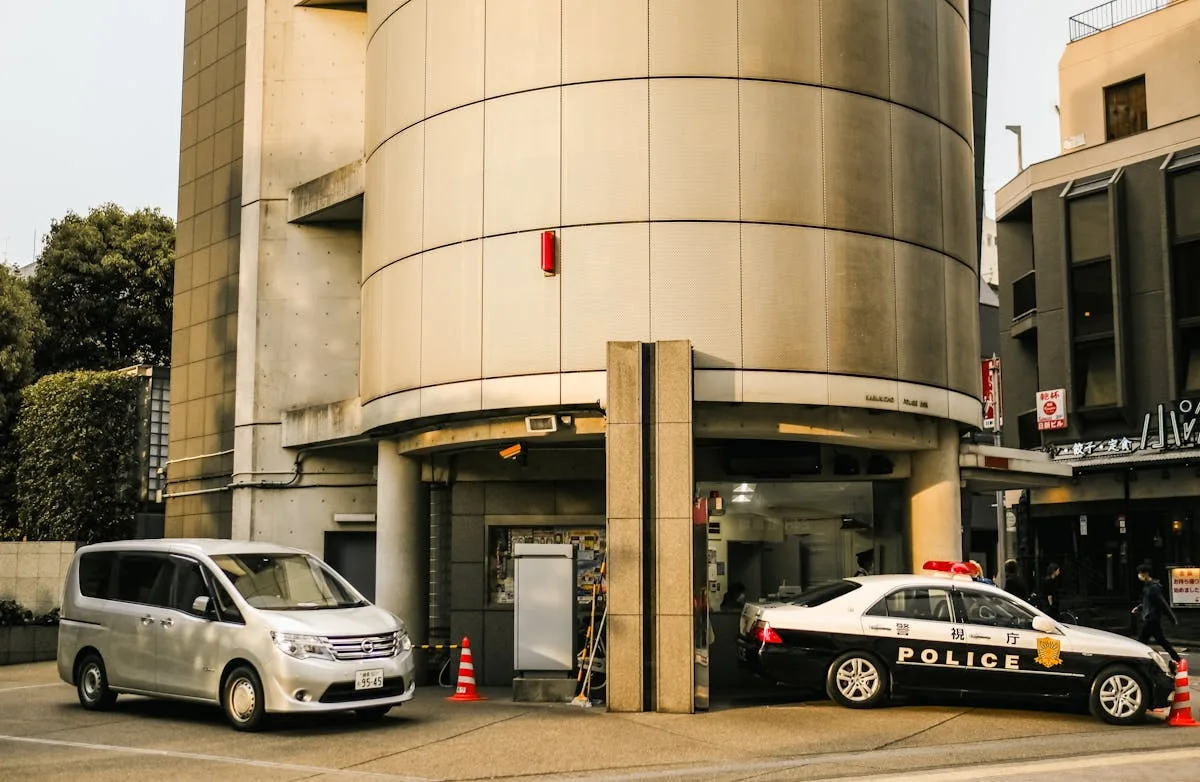 Street view featuring police and Nissan vehicles parked by a modern building.

