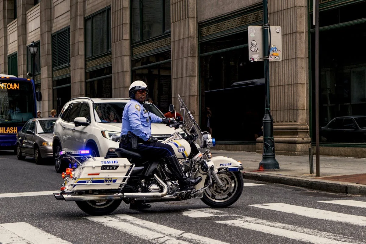 Traffic police officer riding a motorcycle in a busy city intersection.