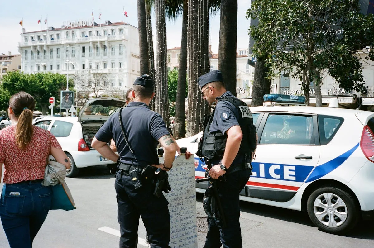 Police officers and a civilian interact near a police car on a busy city street.
