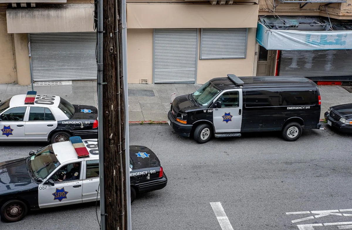 A high angle view of police cars and van on a city street in San Francisco.
