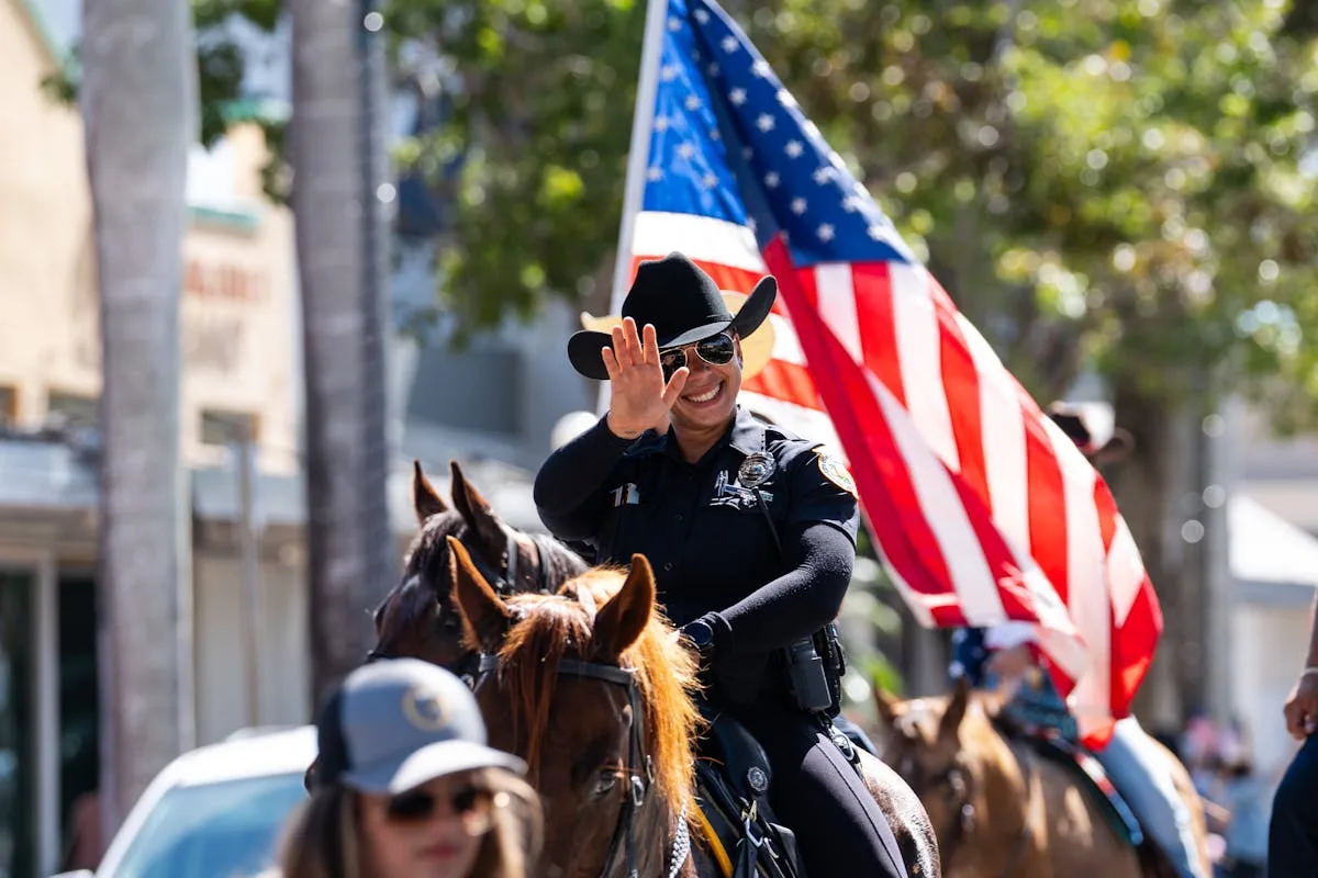 Smiling police officer on horseback during patriotic parade in Miami, Florida.
