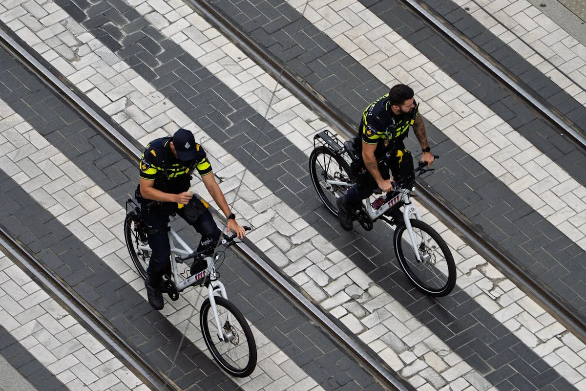 Two police officers on bicycles patrol a city street, highlighting urban law enforcement.