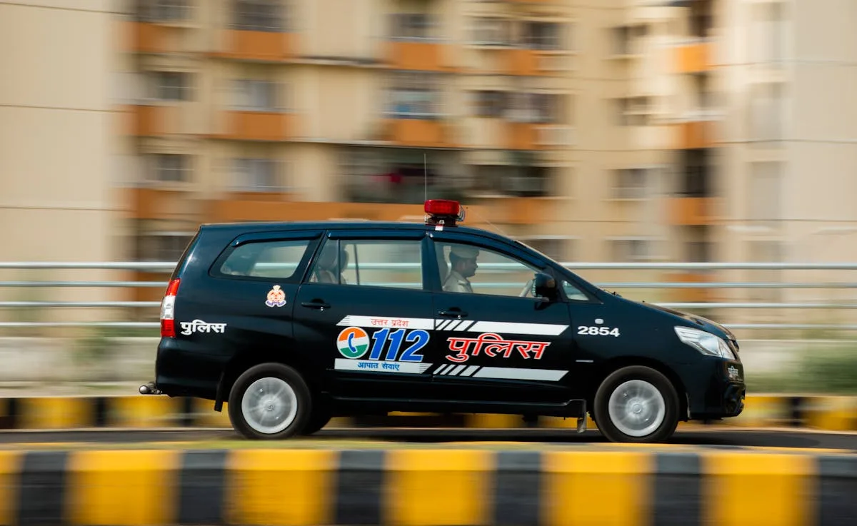 A police car speeds through a city street, showcasing urban emergency response.

