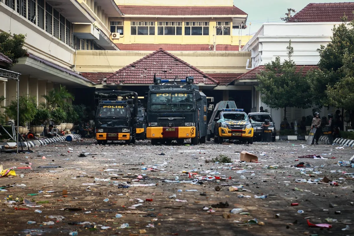 Police vehicles parked in an urban area surrounded by litter and debris.
