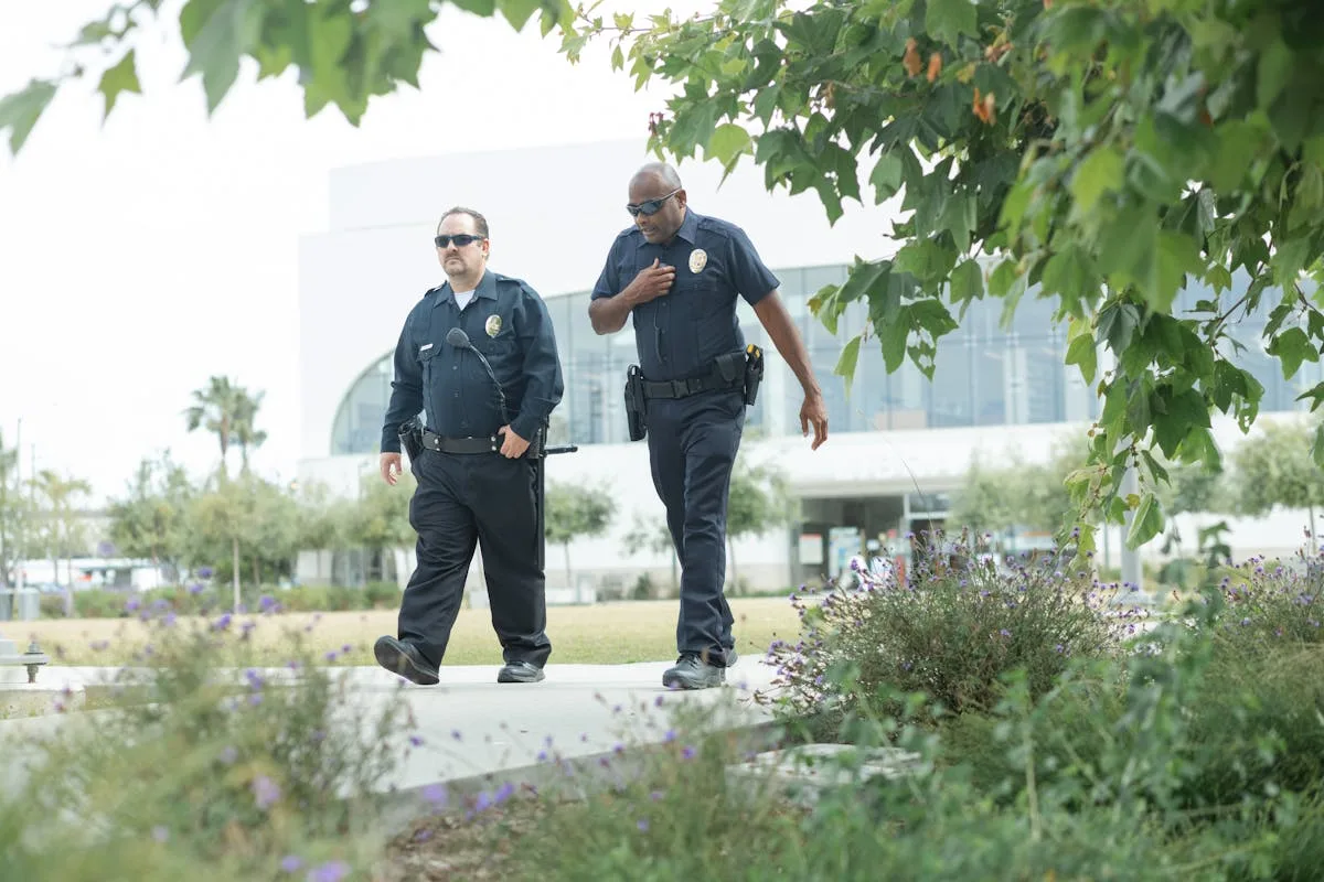 Two police officers in uniform patrol an outdoor urban park area, ensuring public safety and security.
