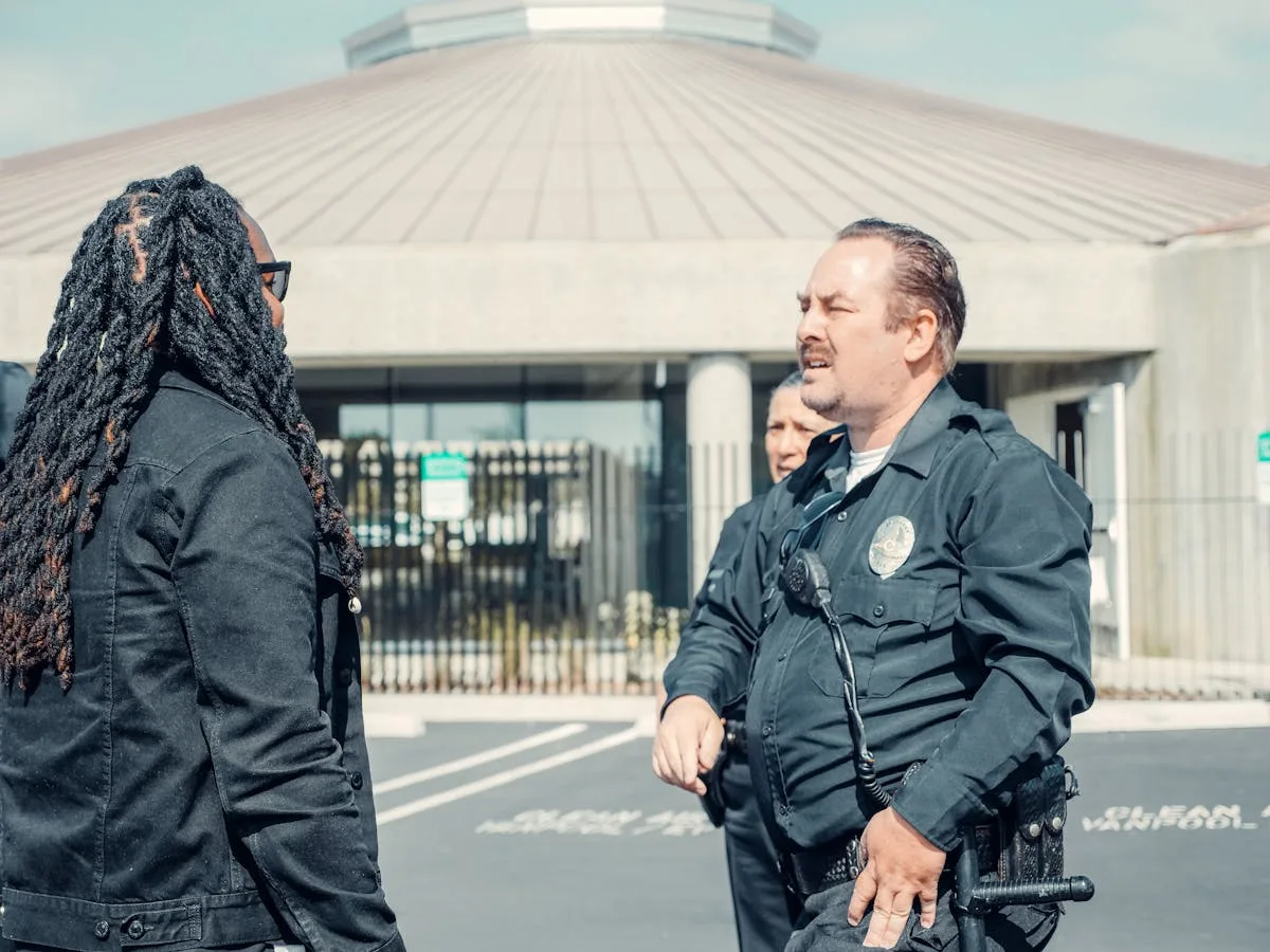 Police officers interacting with a civilian outside a public building, emphasizing community relations.
