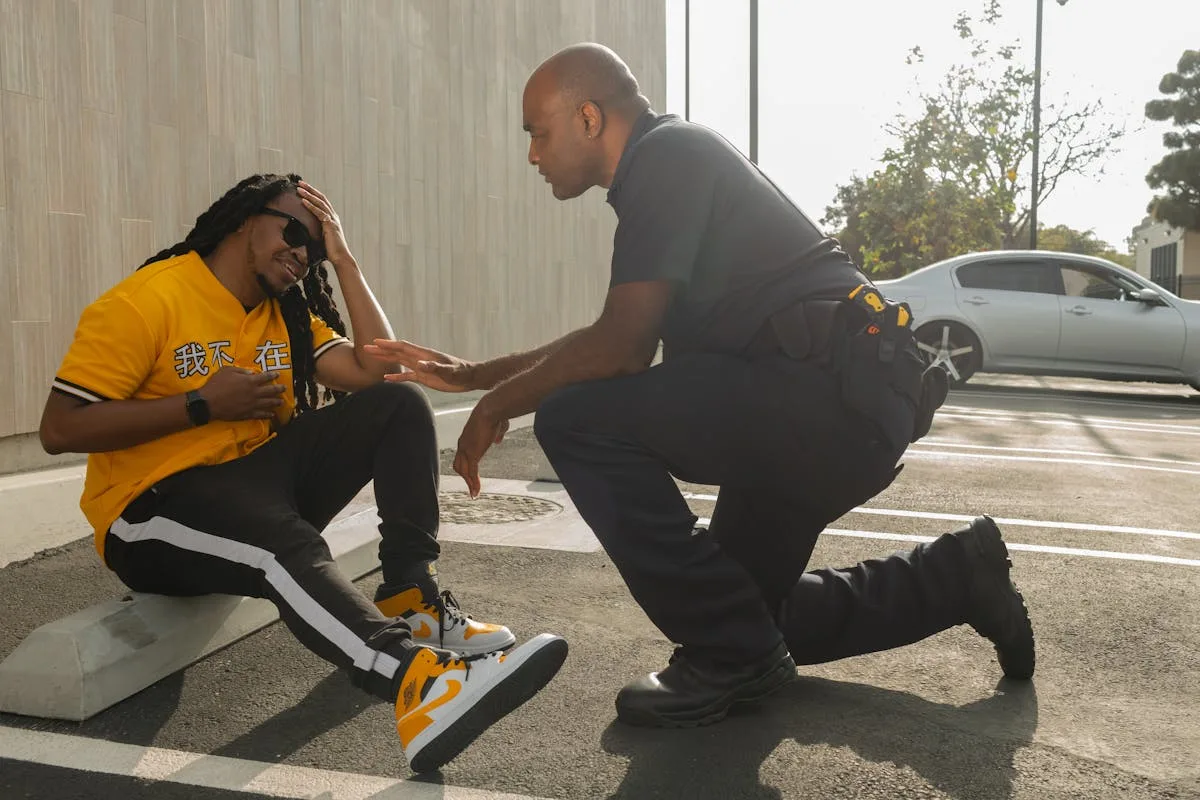 A police officer engages with a seated man outdoors, offering assistance and community support.