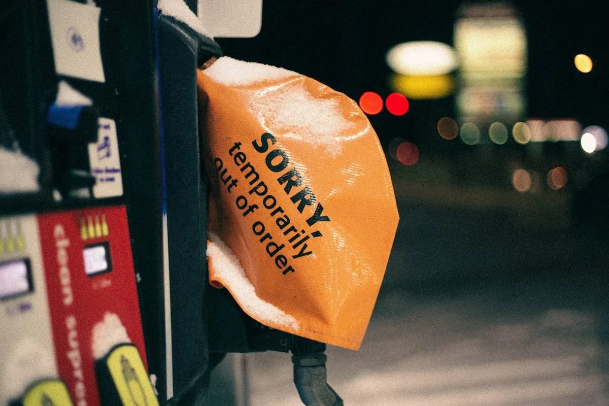 A covered fuel pump in winter with a 'temporarily out of order' sign at night.
