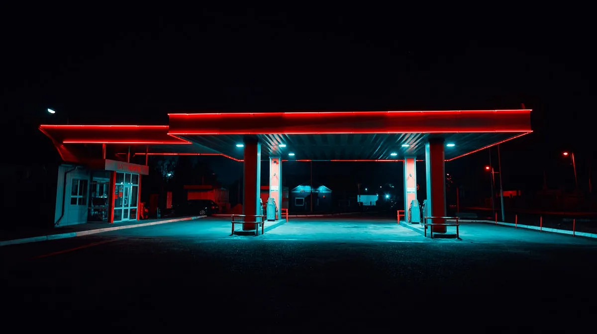 Urban gas station illuminated with vibrant neon lights at night. Modern transportation hub.
